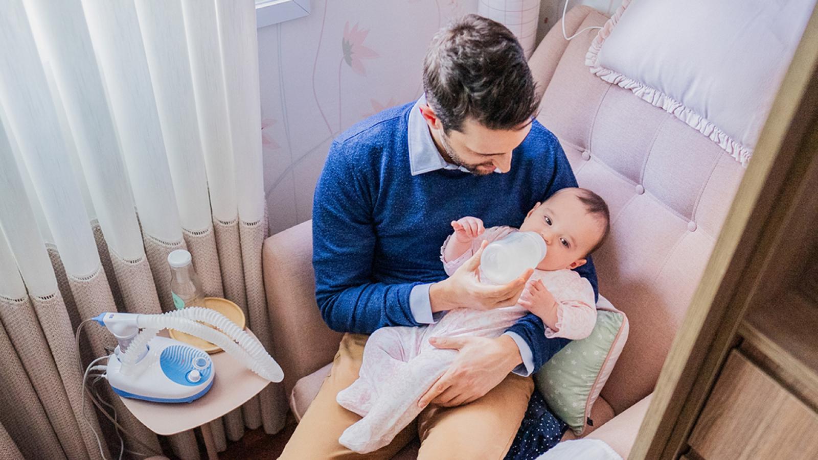 man feeding baby with bottle