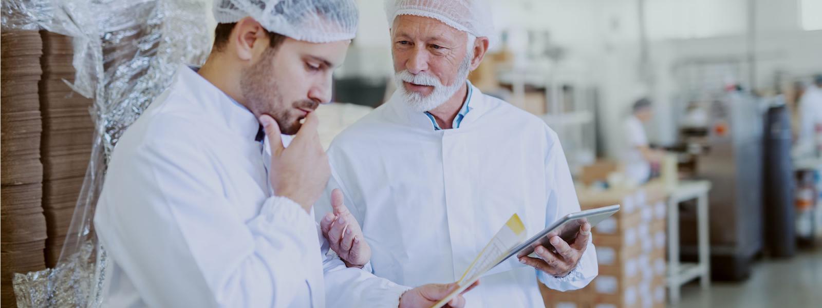 Two men in a factory discussing a food order
