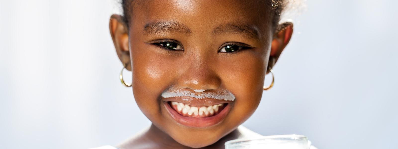 image of smiling child holding a glass of milk